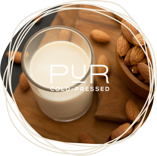 Glass of almond milk surrounded by raw almonds on a wooden board.