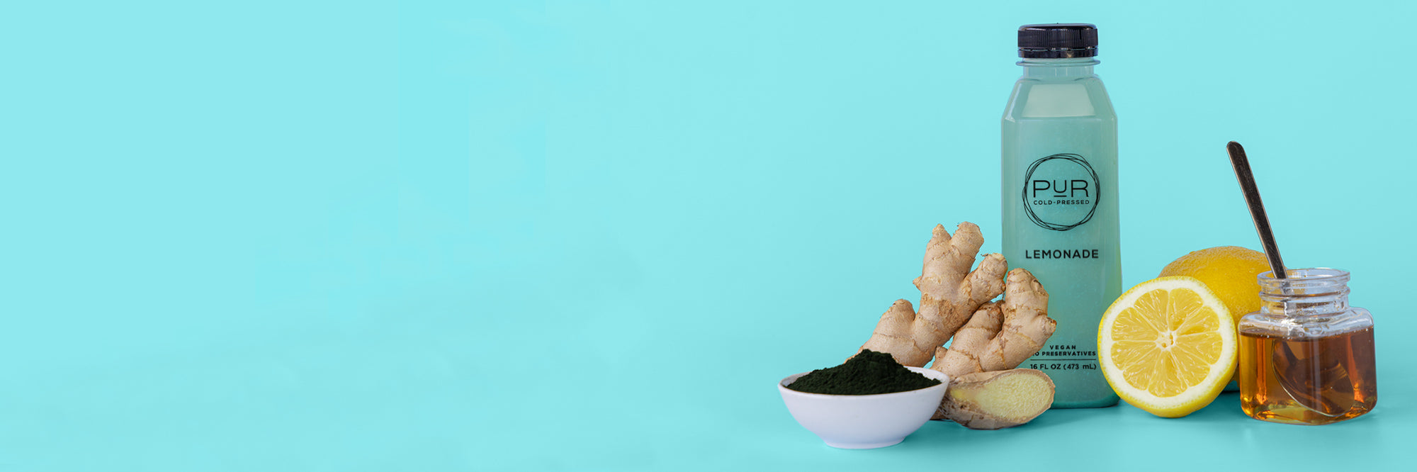 PUR Cold Pressed Blue Lemonade juice with lemon, honey, ginger, and spirulina on a light blue background.