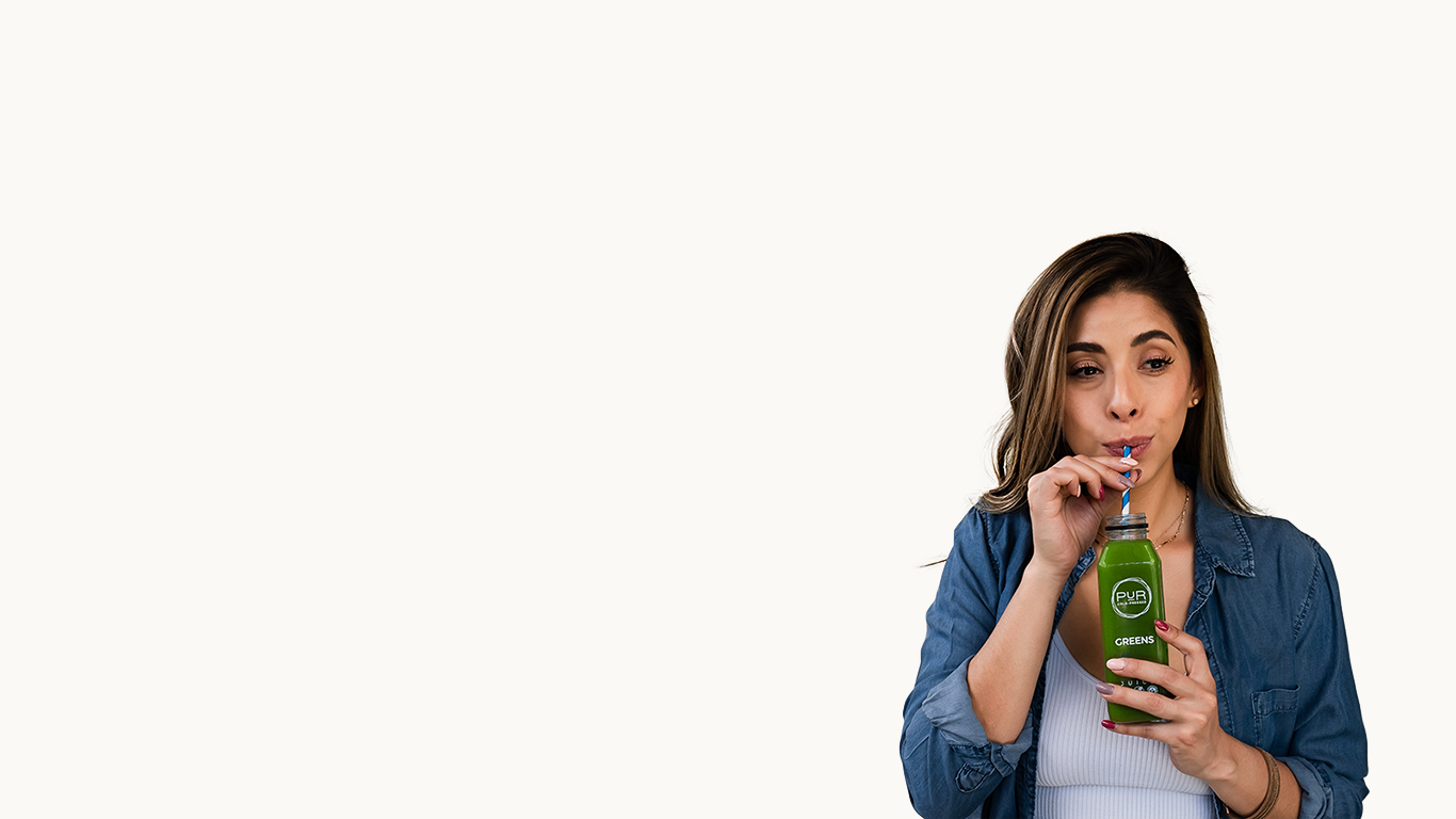 Woman drinking from a PUR greens bottle with a white background
