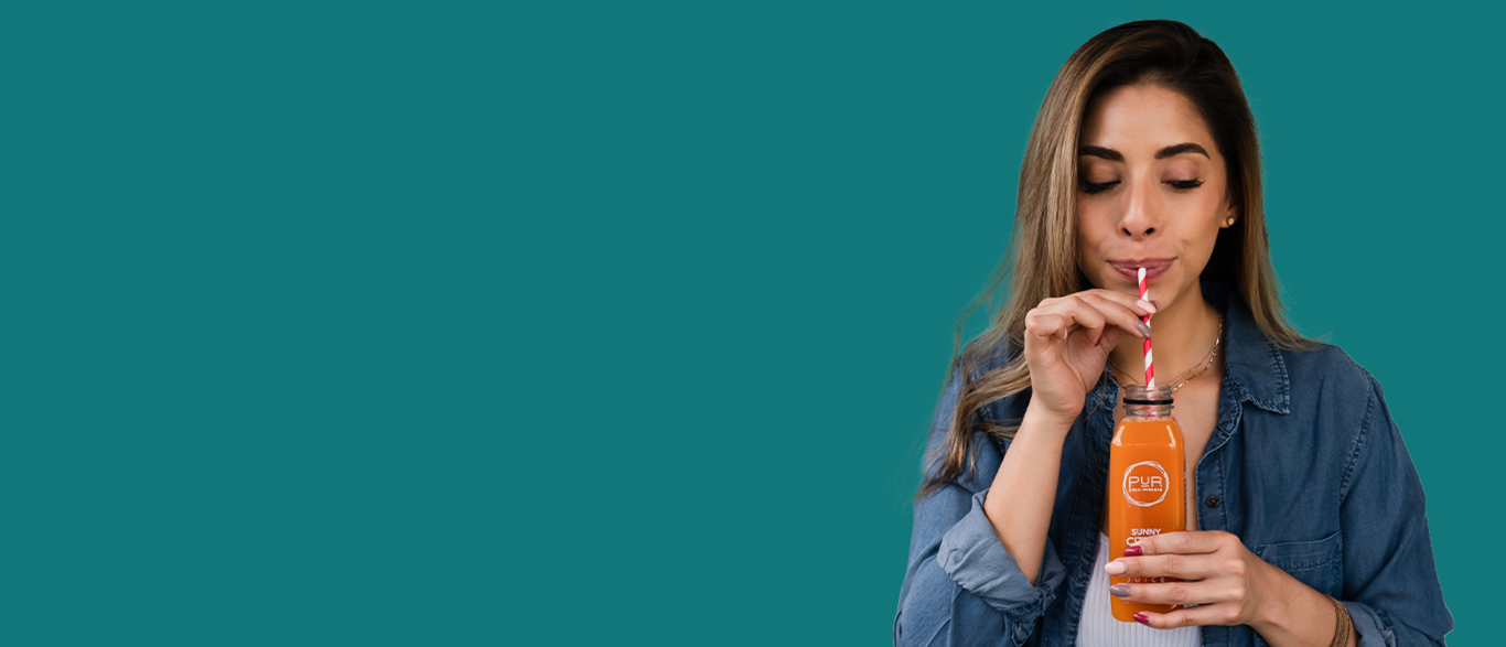 Woman drinking from a PUR sunny citrus bottle with a straw against a teal background